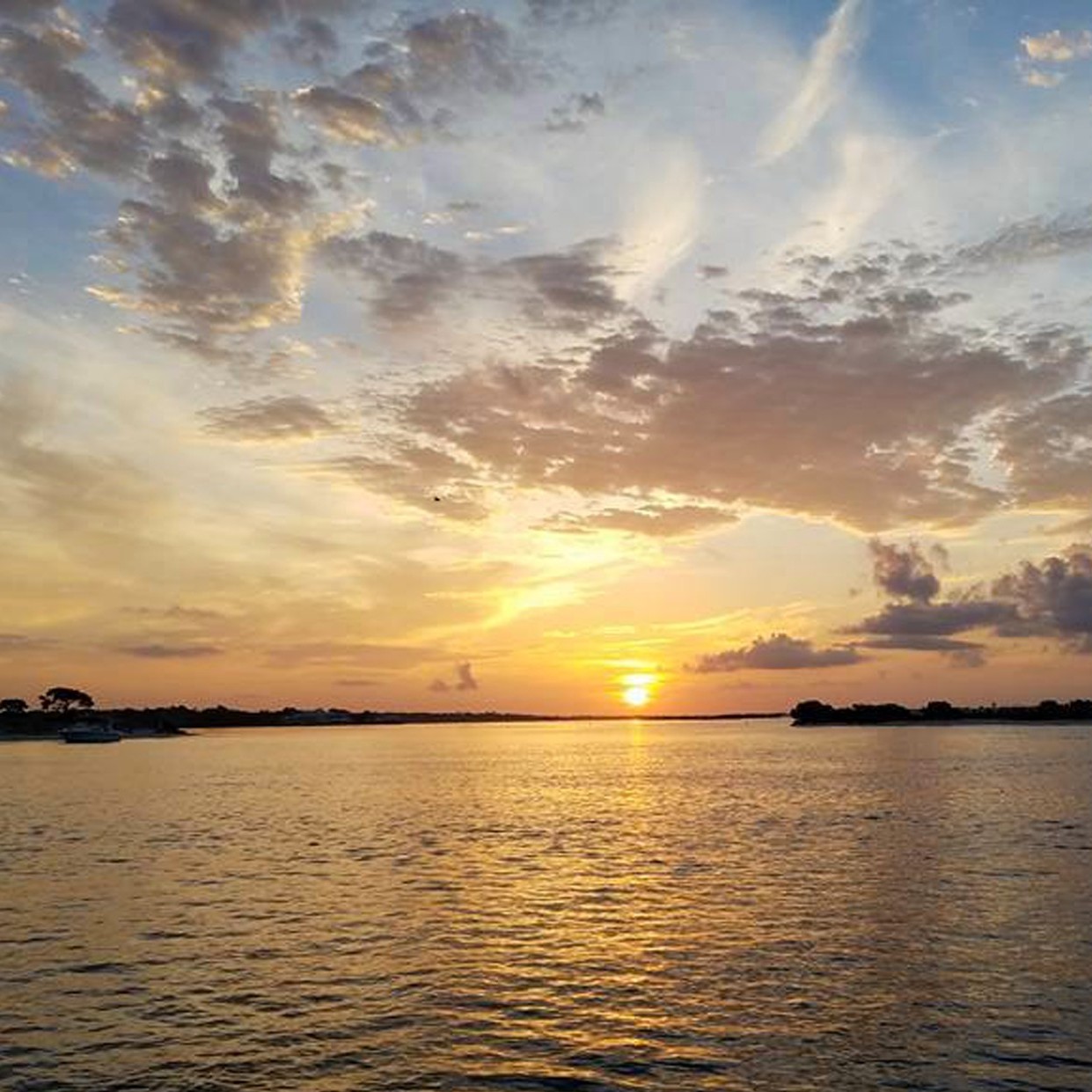 Sunset over calm waters in Gulf Shores AL with golden sky reflection