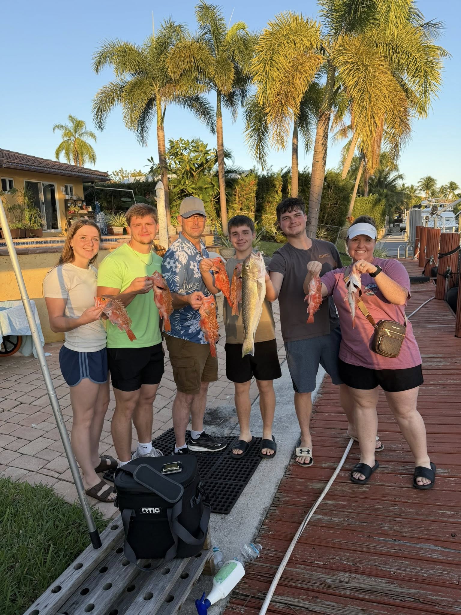 Successful fishing trip in Pompano Beach FL with fresh caught fish displayed on dock with palm trees