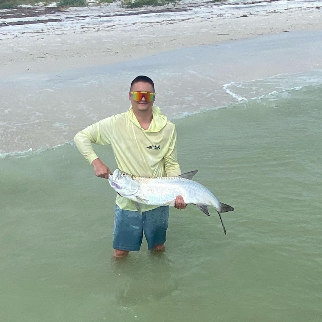 A fisherman holding a large tarpon fish in Clearwater