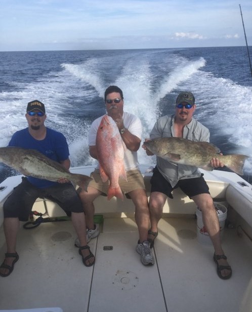 Three large fish displayed on boat deck after deep sea fishing trip in Port Canaveral FL, including gag grouper and red snapper