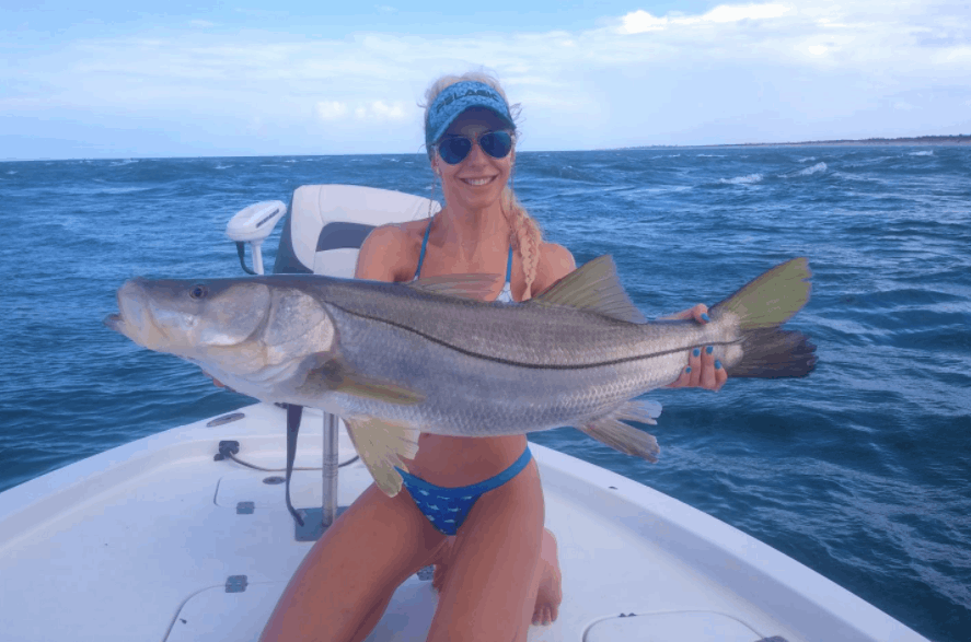 A fisherman posing with a large snook caught in Grant-Valkaria