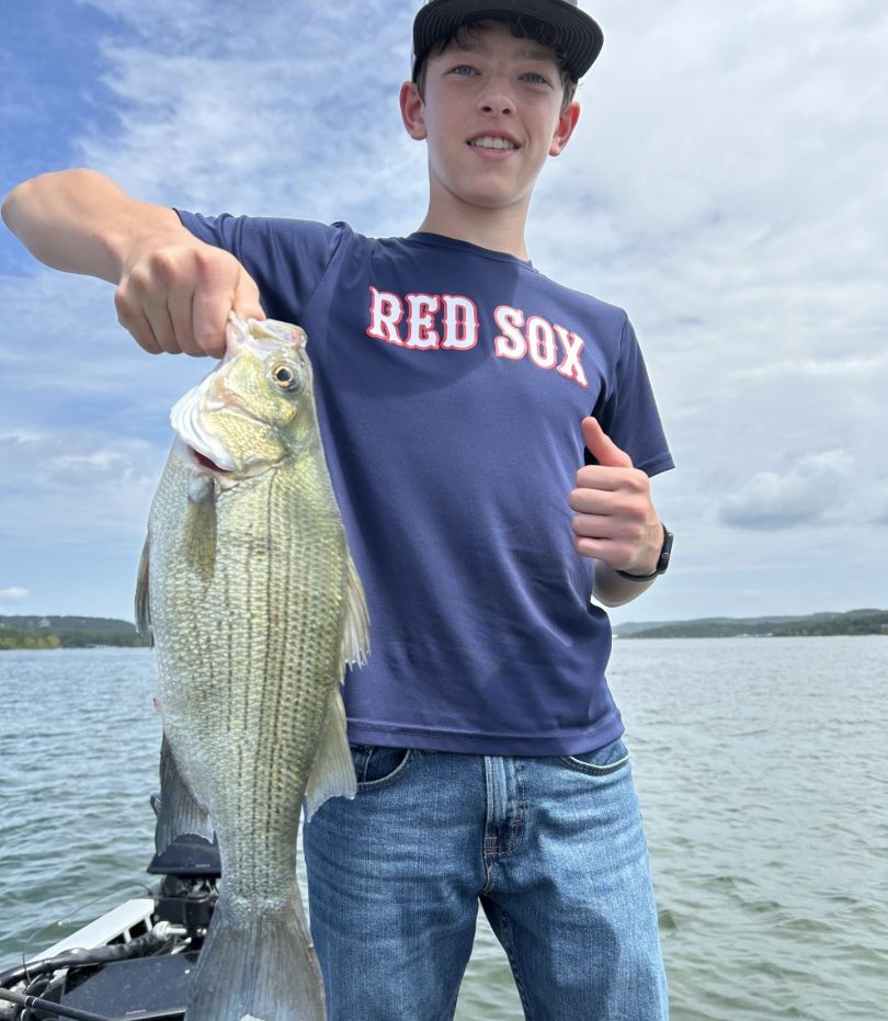 Angler holding caught bass fish on lake in Branson MO
