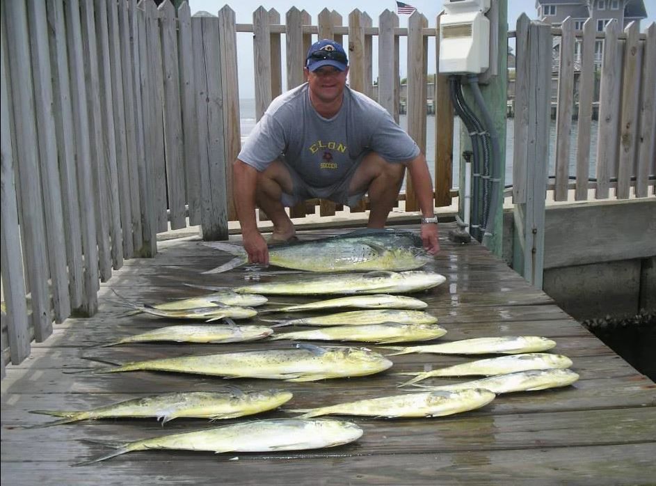 A fisherman holds two big fish while fishing in NC.