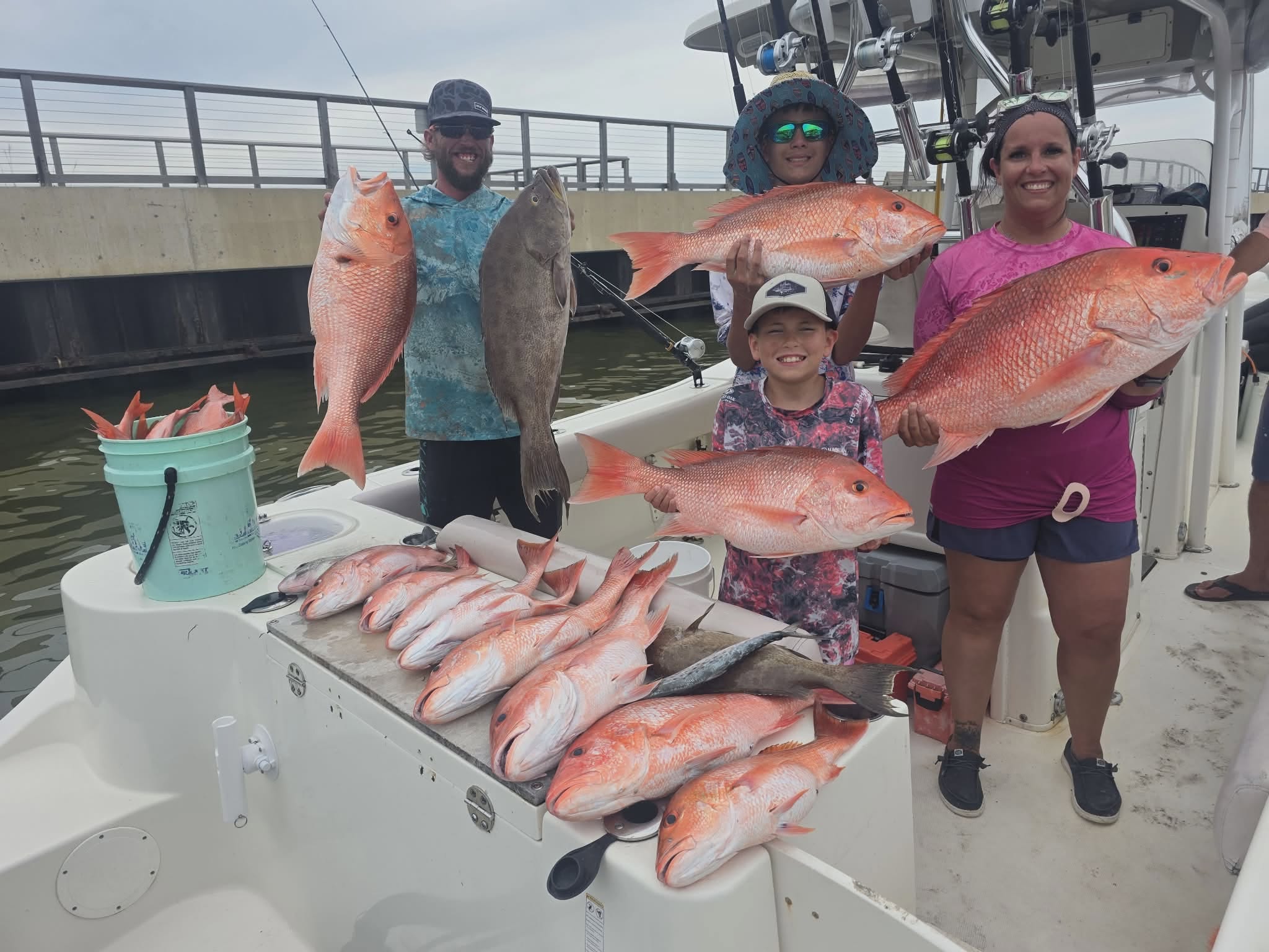 Successful red snapper fishing trip in Gulf Shores AL with multiple large fish displayed on boat deck
