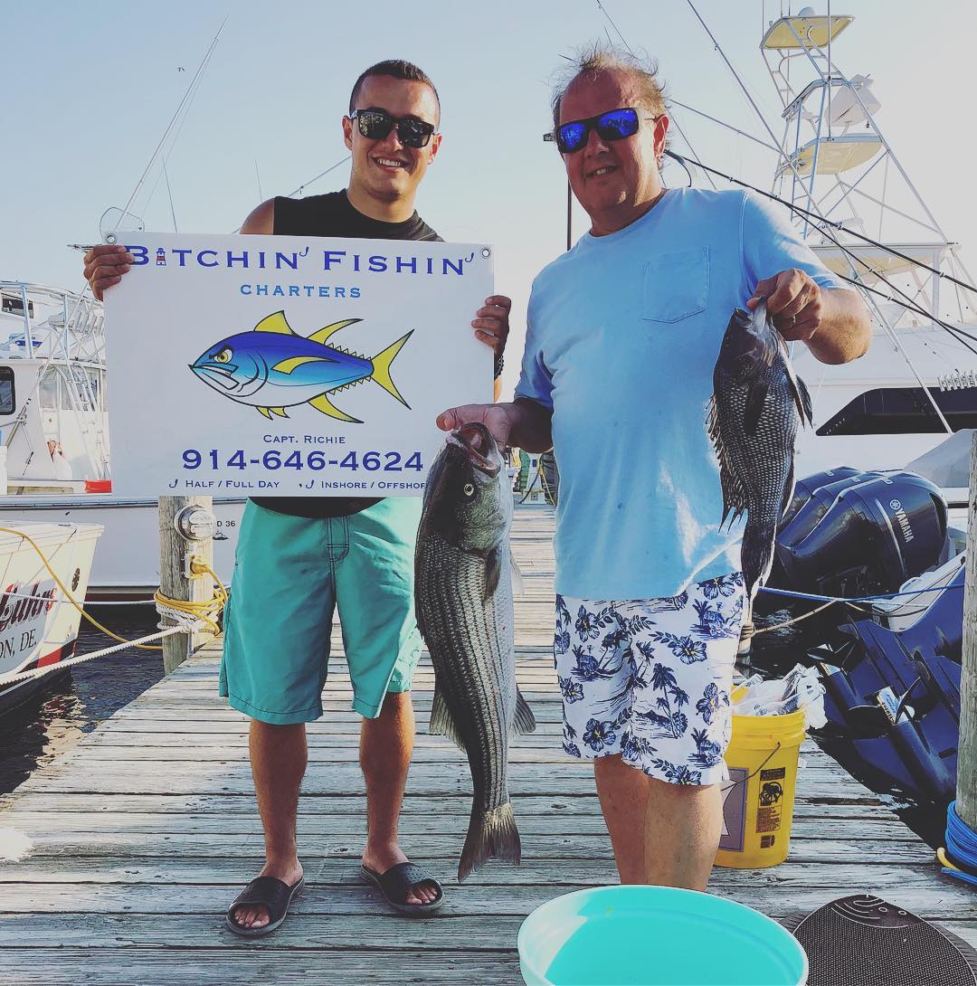Two anglers holding three striped bass and sea bass fish in Montauk