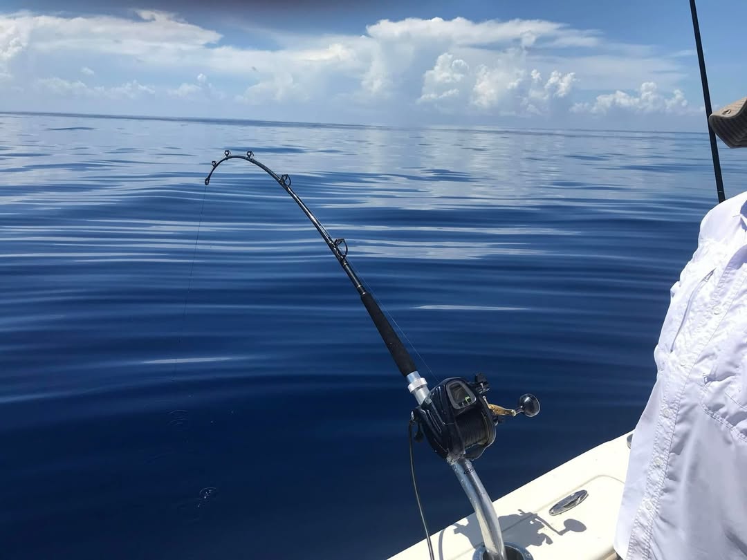 Fishing rod with reel positioned over calm blue ocean waters from boat deck in Grant-Valkaria FL
