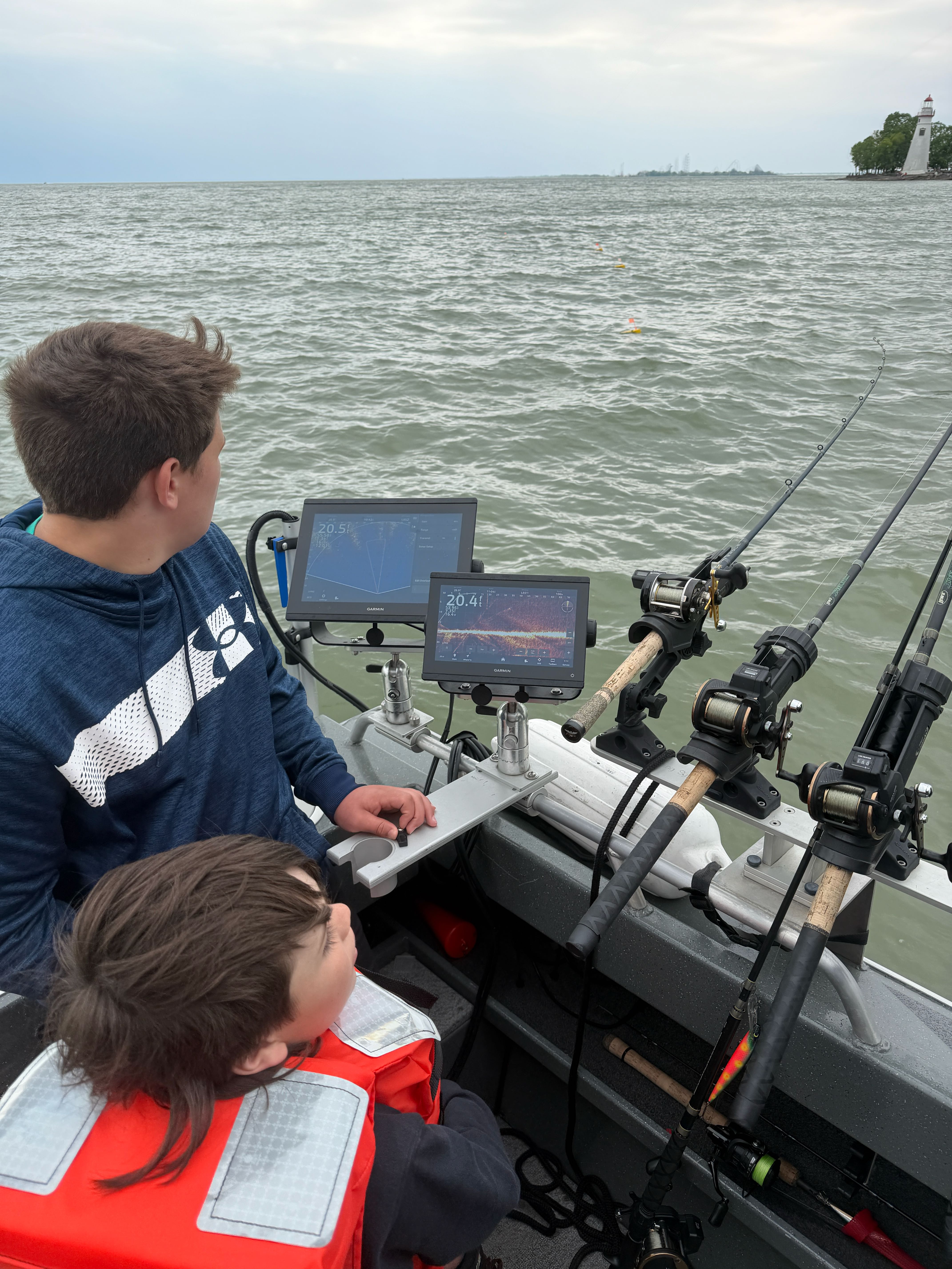 Fishing boat equipped with sonar screens and fishing rods on water near Spencerville OH lighthouse