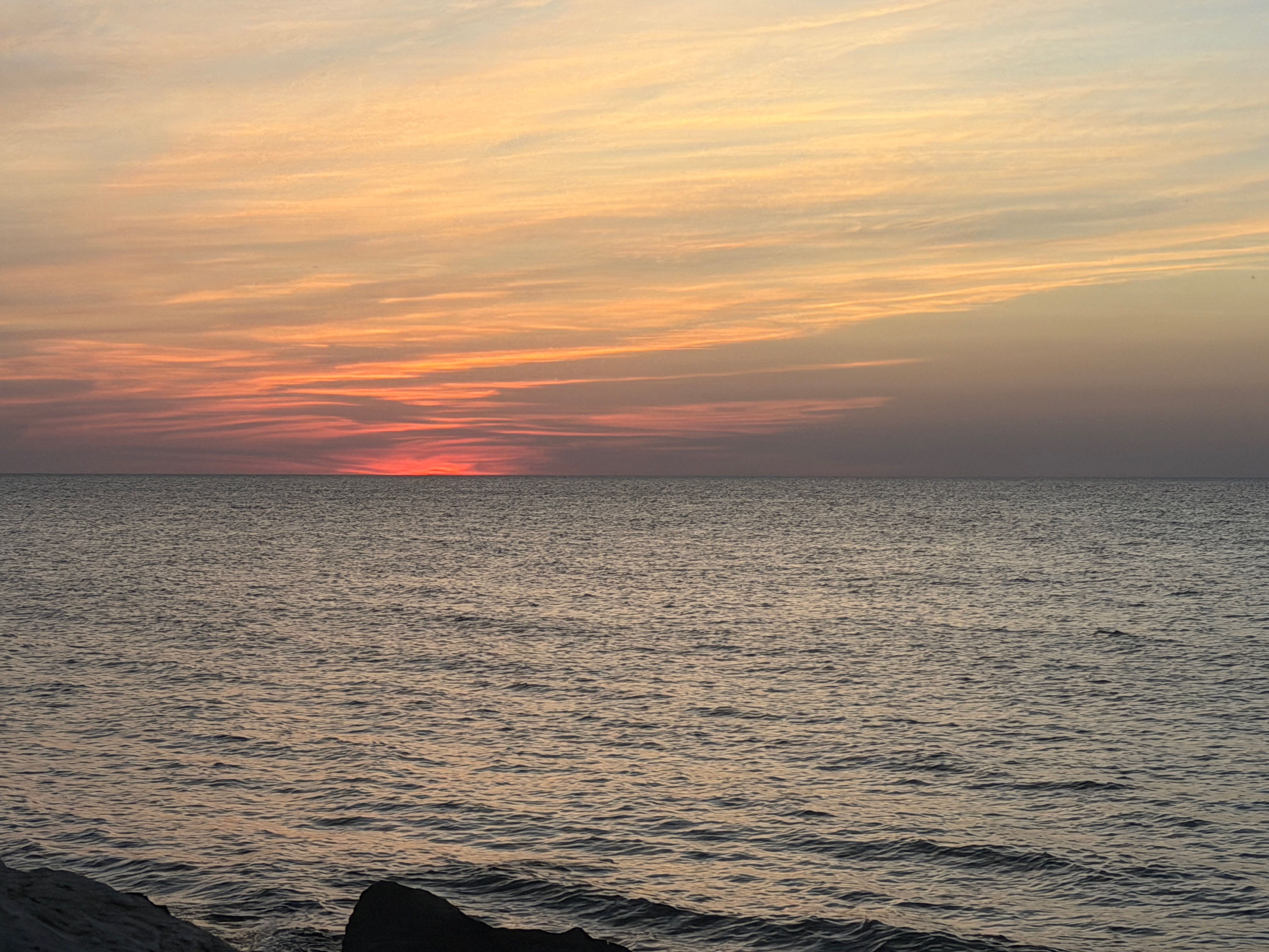 Sunset over calm ocean waters with gentle waves and colorful sky in Spencerville OH