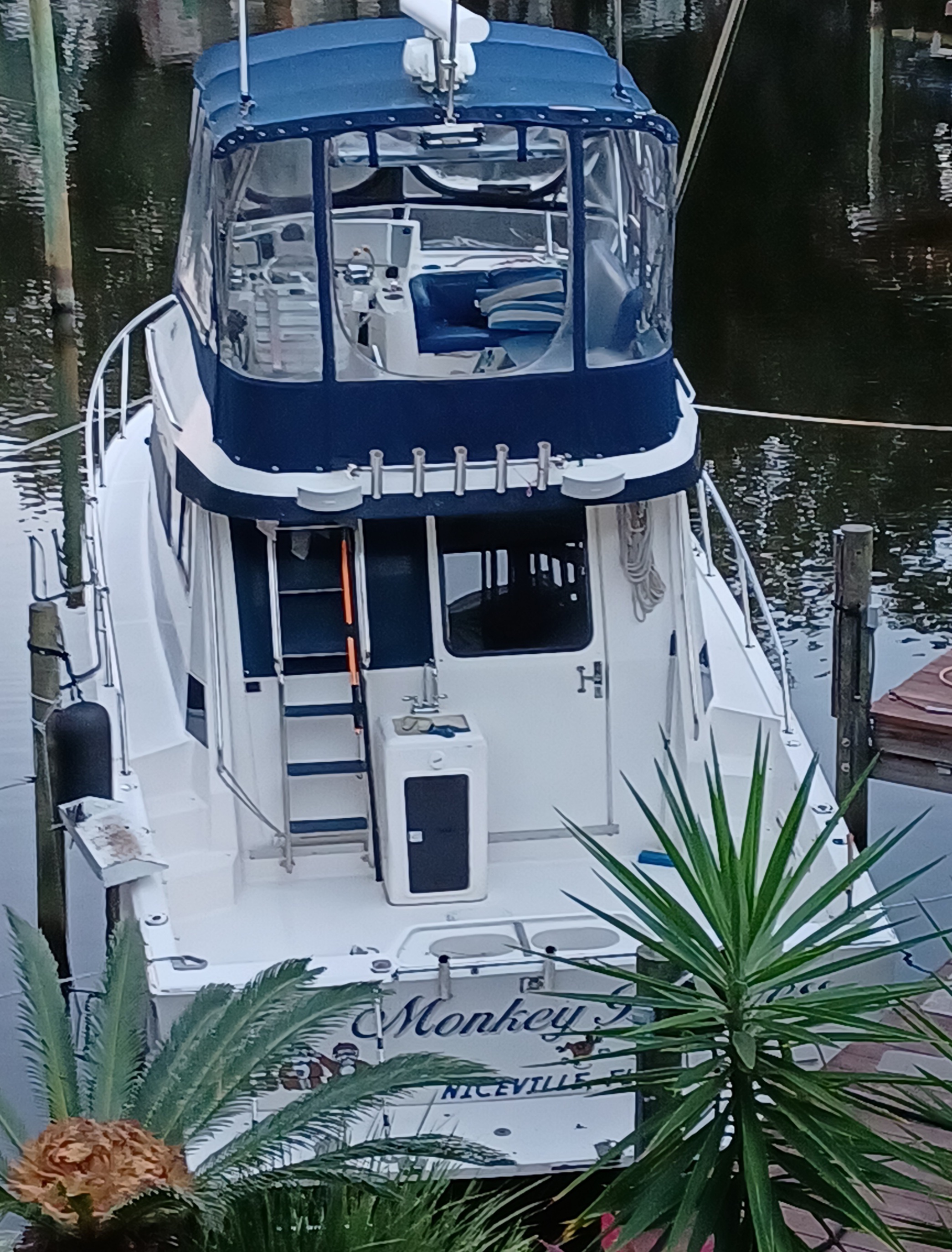 Fishing boat named Monkey F docked at marina in Fort Walton Beach FL with blue canvas top and white hull