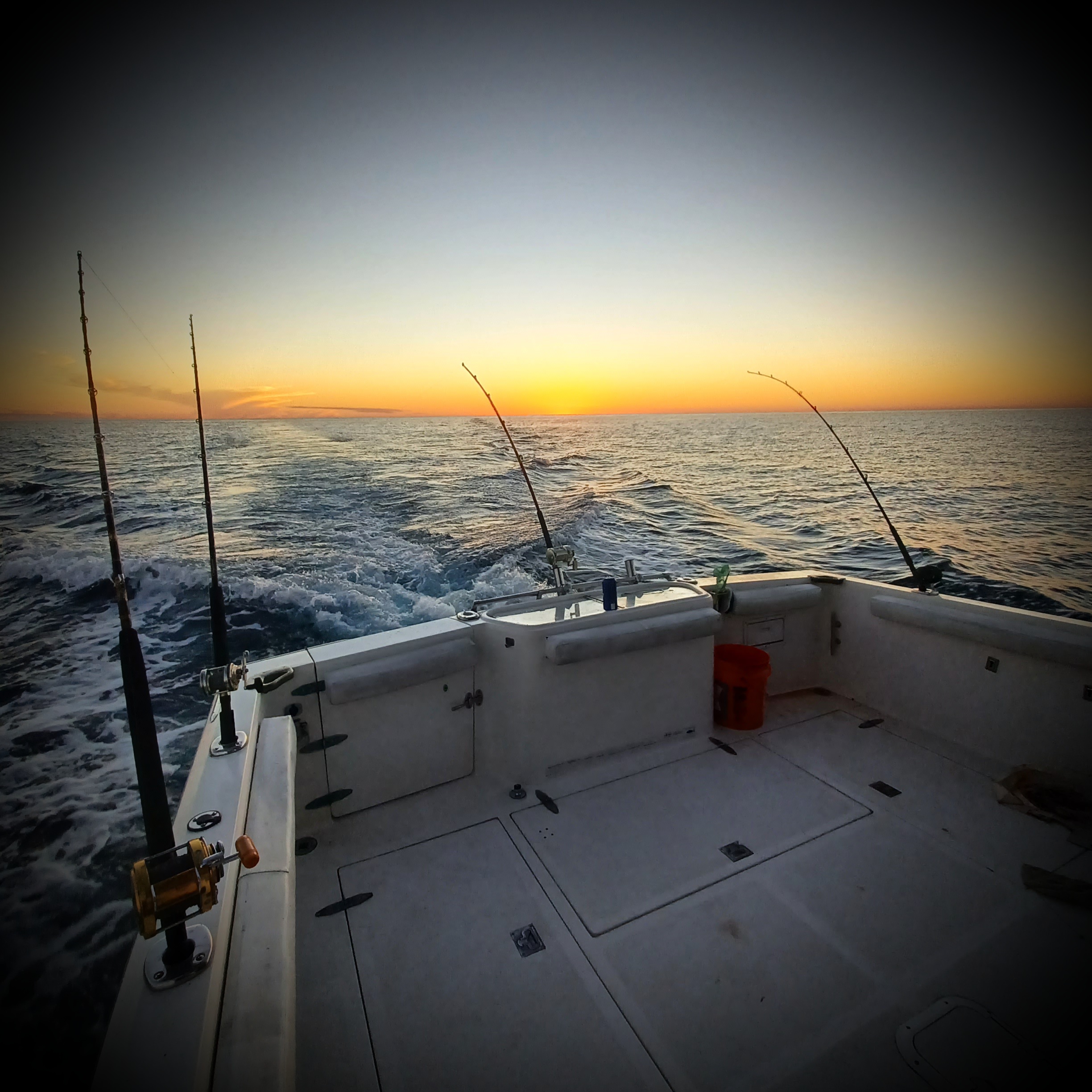 Fishing boat with multiple rods set up on the stern deck at sunset over the ocean near Fort Walton Beach FL
