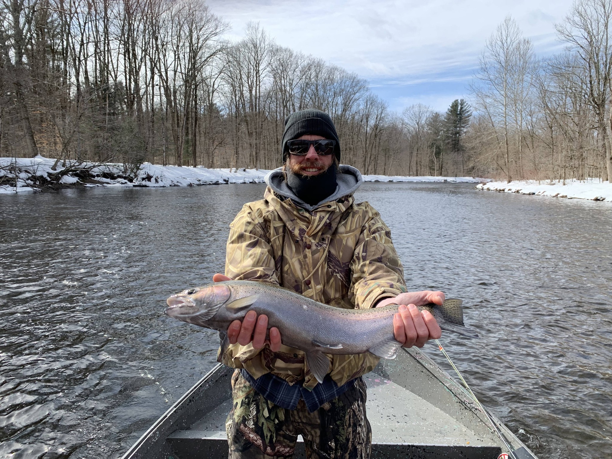Angler holding large steelhead trout on snowy river in Altmar NY during winter fishing trip