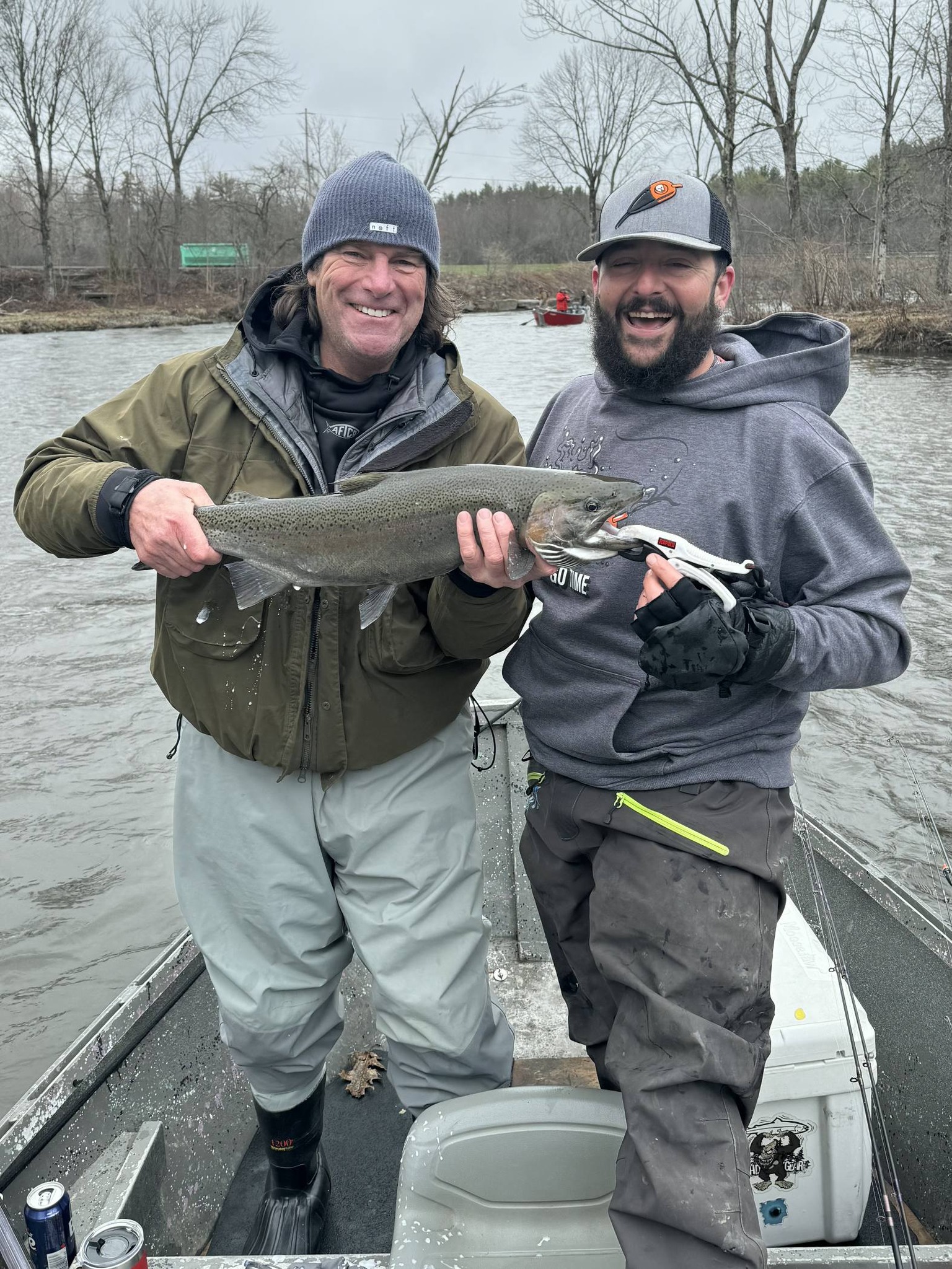 Two anglers holding a rainbow trout on boat in Altmar NY river