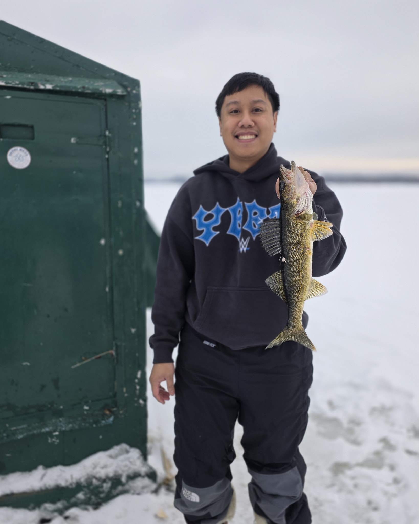 Walleye caught during ice fishing in Gravenhurst ON with green ice hut in snowy winter conditions