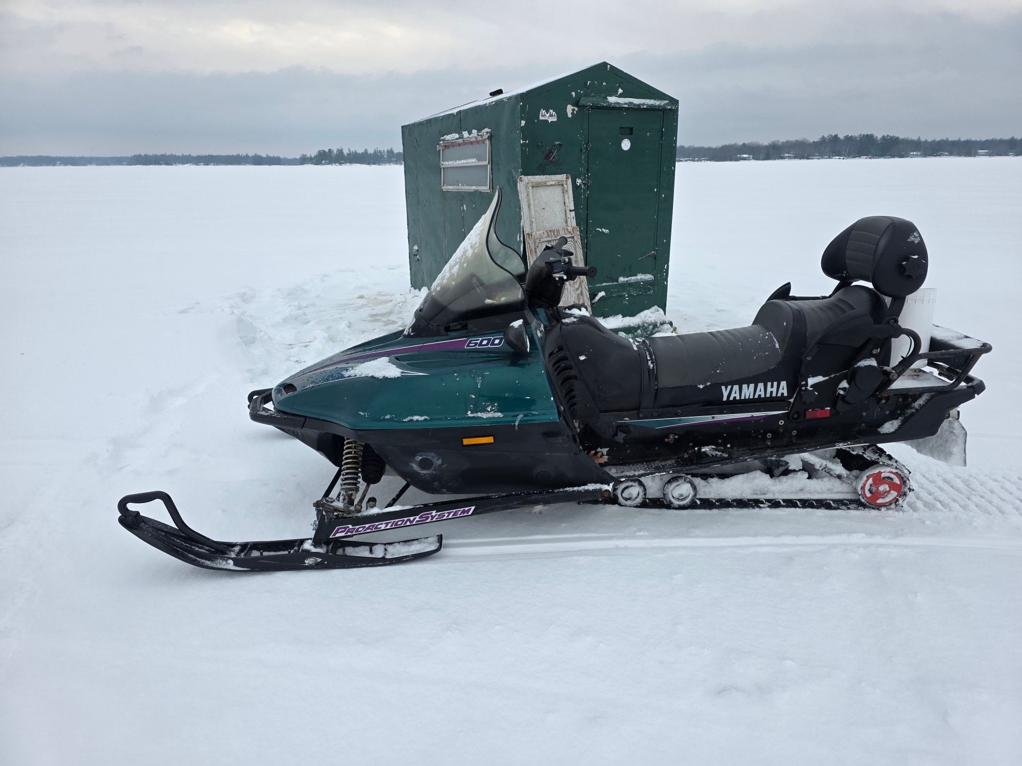 Yamaha snowmobile parked next to green ice fishing hut on frozen lake in Gravenhurst ON
