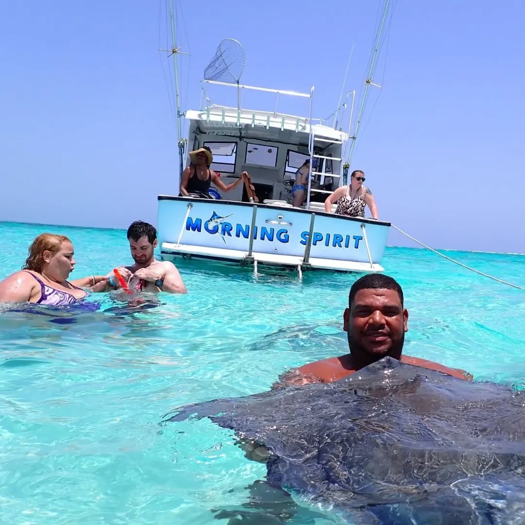 Stingray encounter during fishing excursion in Cayman Islands crystal clear waters with boat named Morning Spirit
