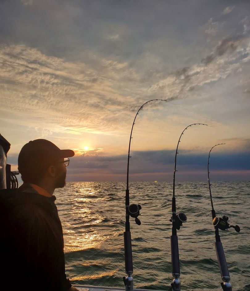 Fishing rods with reels positioned over water at sunset near Lakeside Marblehead OH
