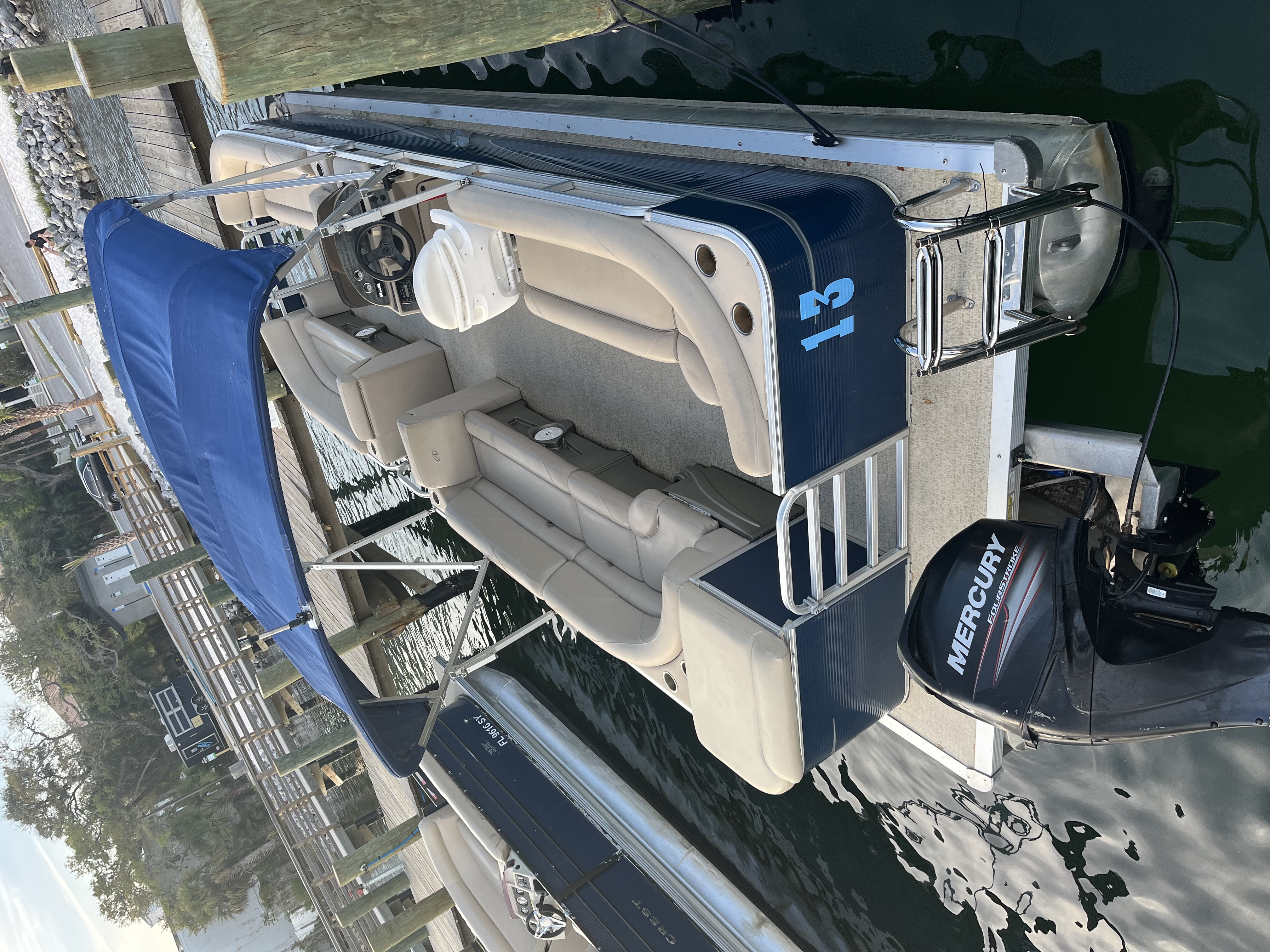 Luxury pontoon boat with comfortable seating and outboard motor docked at marina