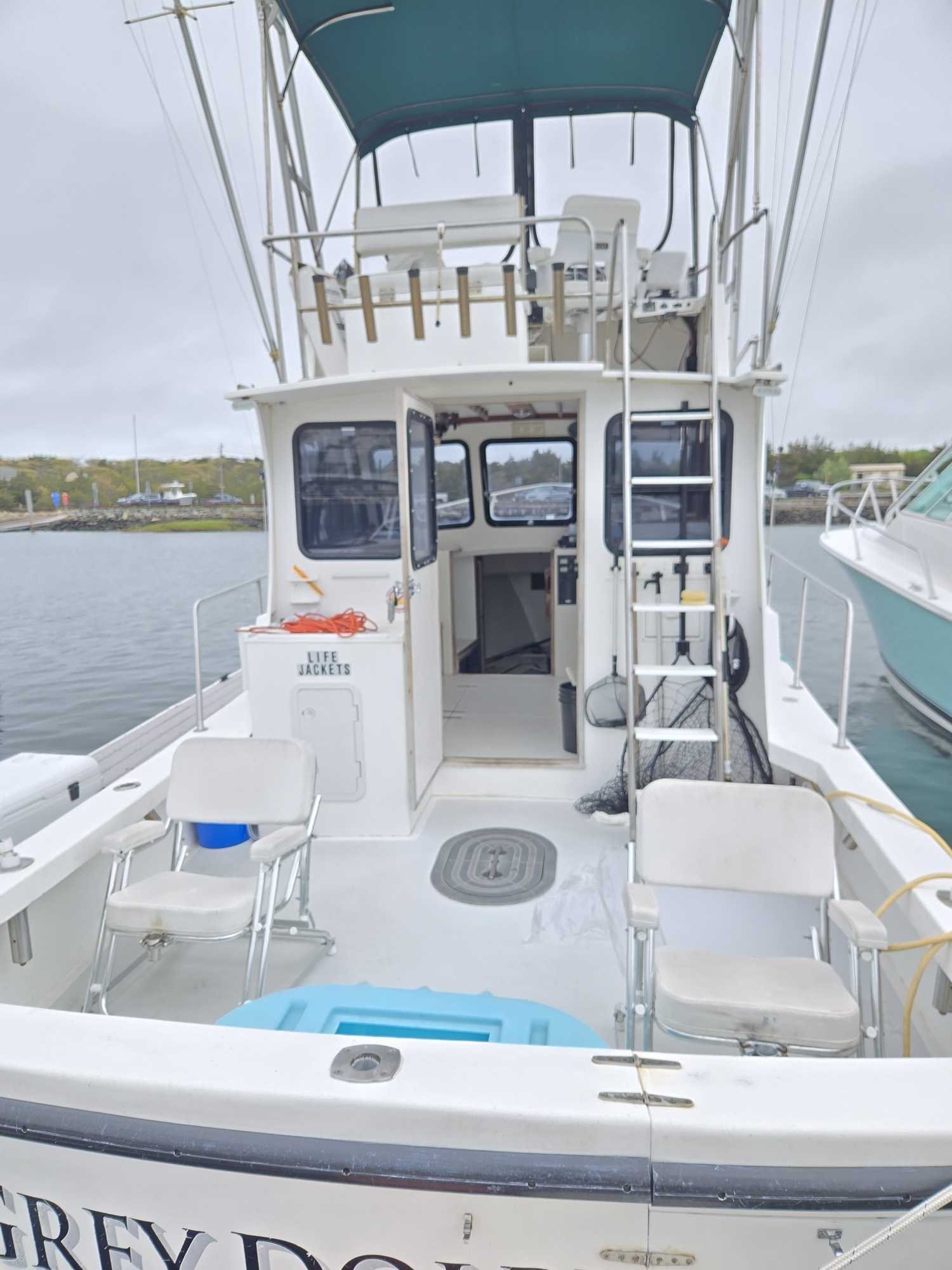White fishing boat with upper deck and cabin docked at Cape Cod marina