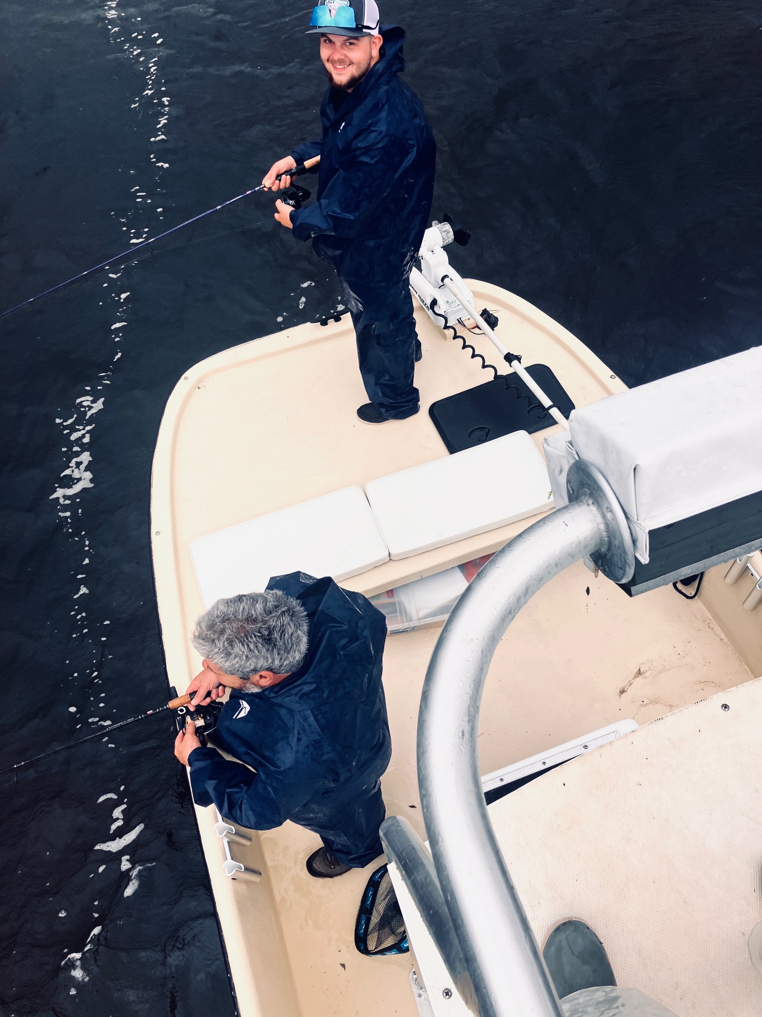 Fishing charter boat with anglers holding rods in dark water near Bagdad FL