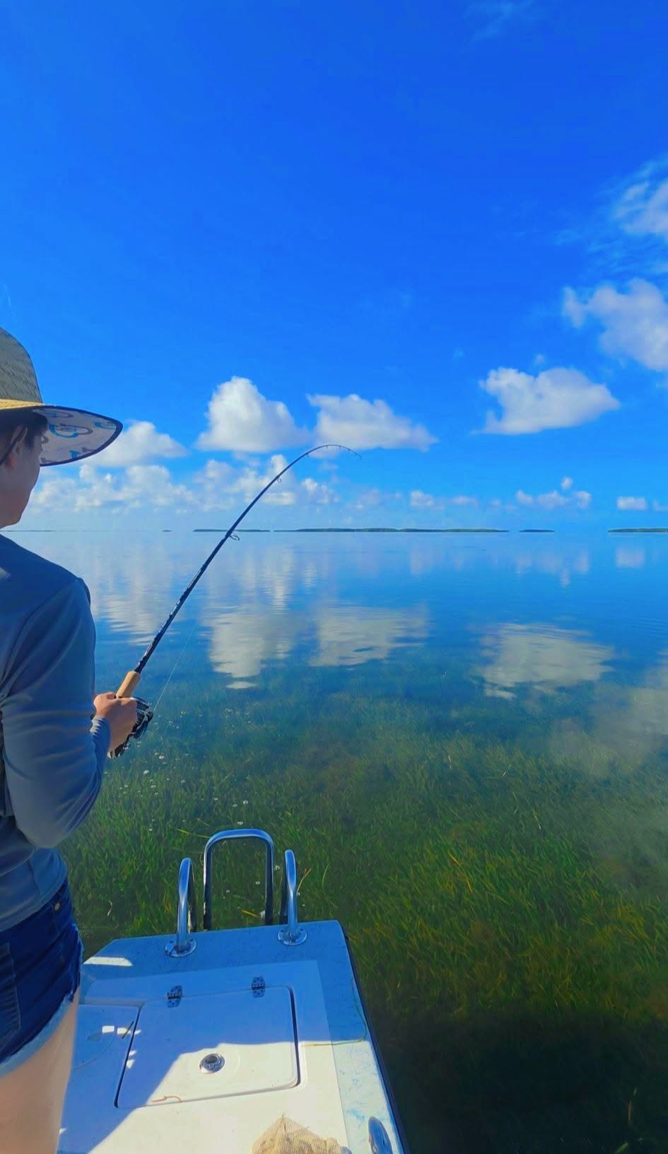 Fishing from boat in clear shallow waters of Citrus County FL with bent fishing rod