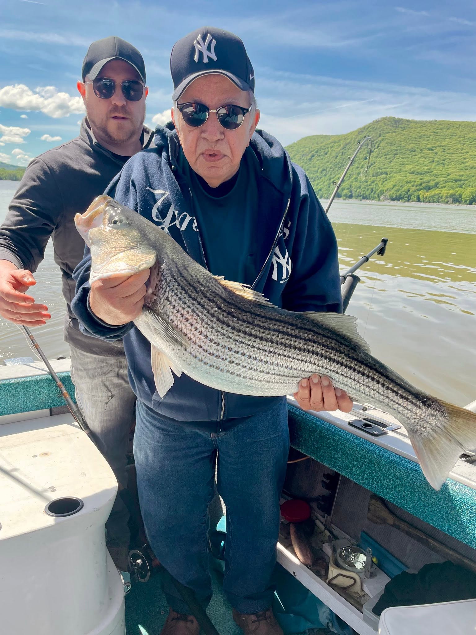 Striped bass caught during fishing trip in Mexico NY on boat with scenic lake and forested hills