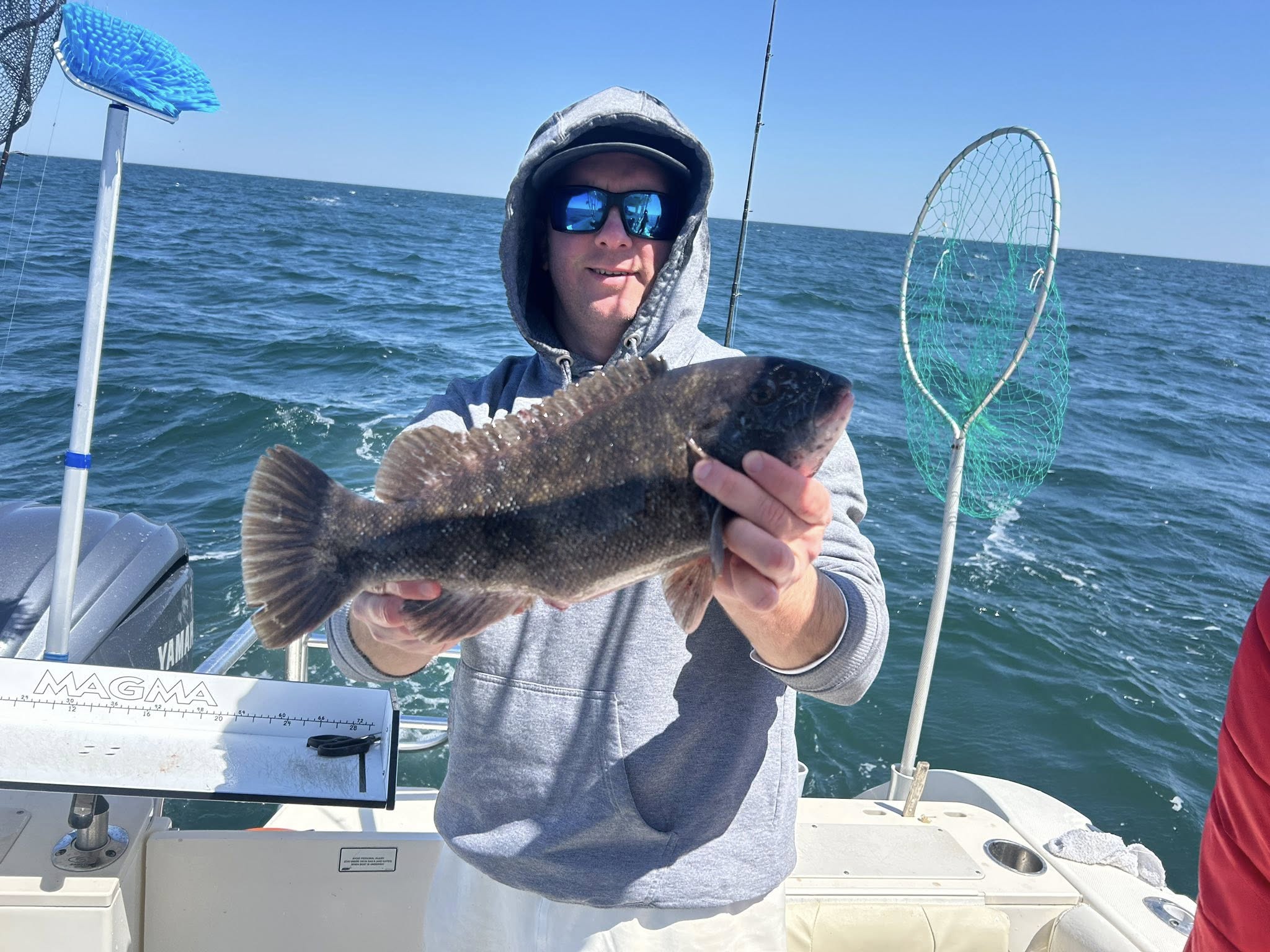 Angler holding caught tautog fish on boat in Sea Isle City NJ waters
