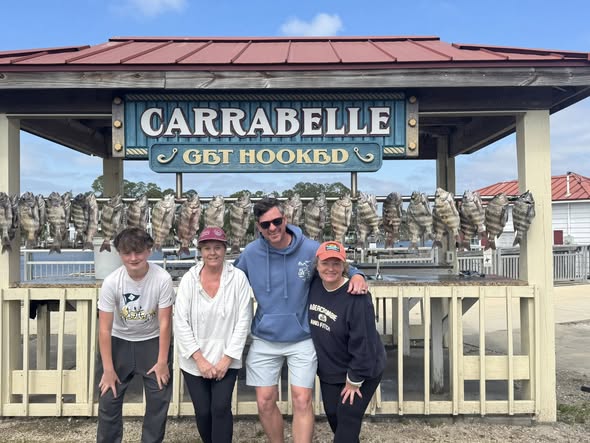 Fishing charter group posing at Carrabelle marina dock with charter boat in background