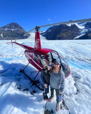 Red helicopter landed on snowy glacier in Alaska mountains for fishing expedition