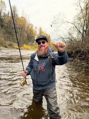 Angler holding caught fish while standing in river in Willow Alaska