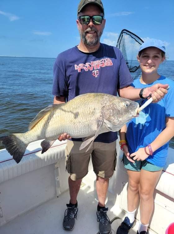 A large black drum fish caught by two people in Biloxi