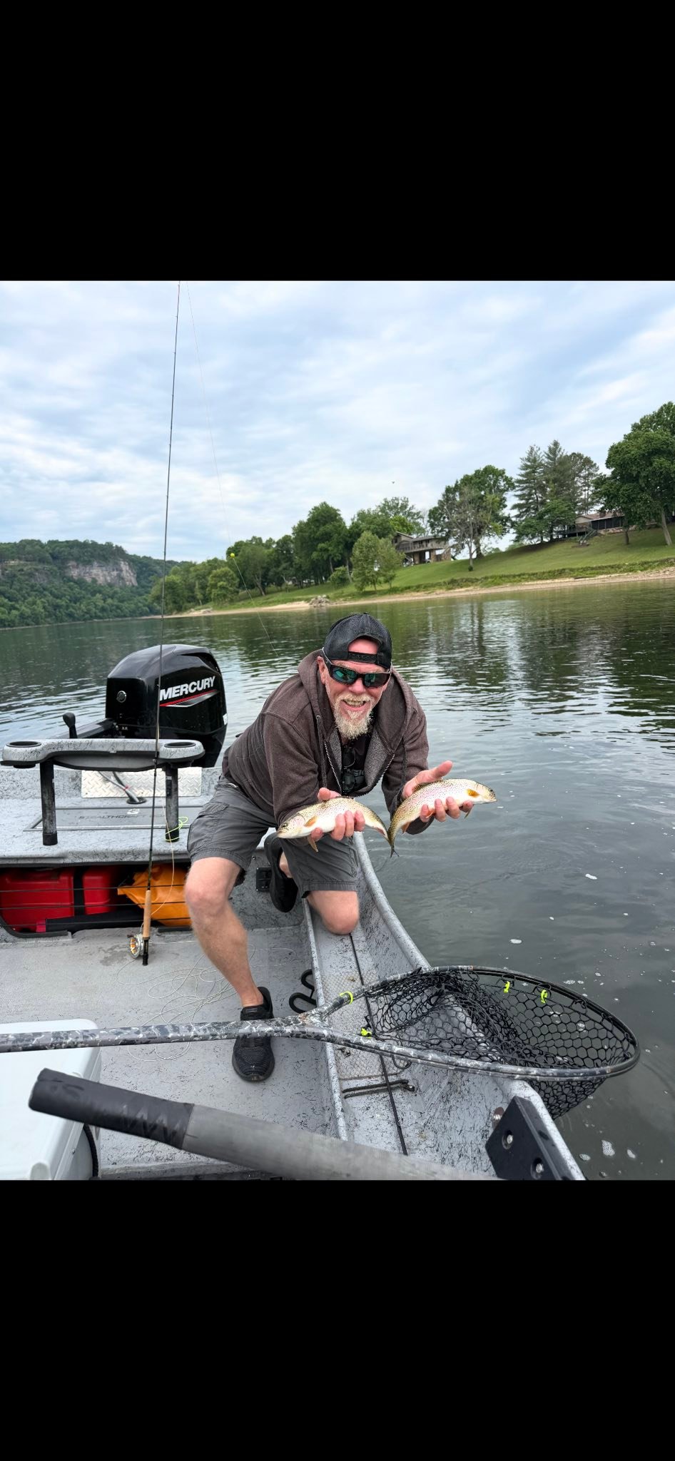 Angler displaying two freshly caught fish on fishing boat in Cotter AR