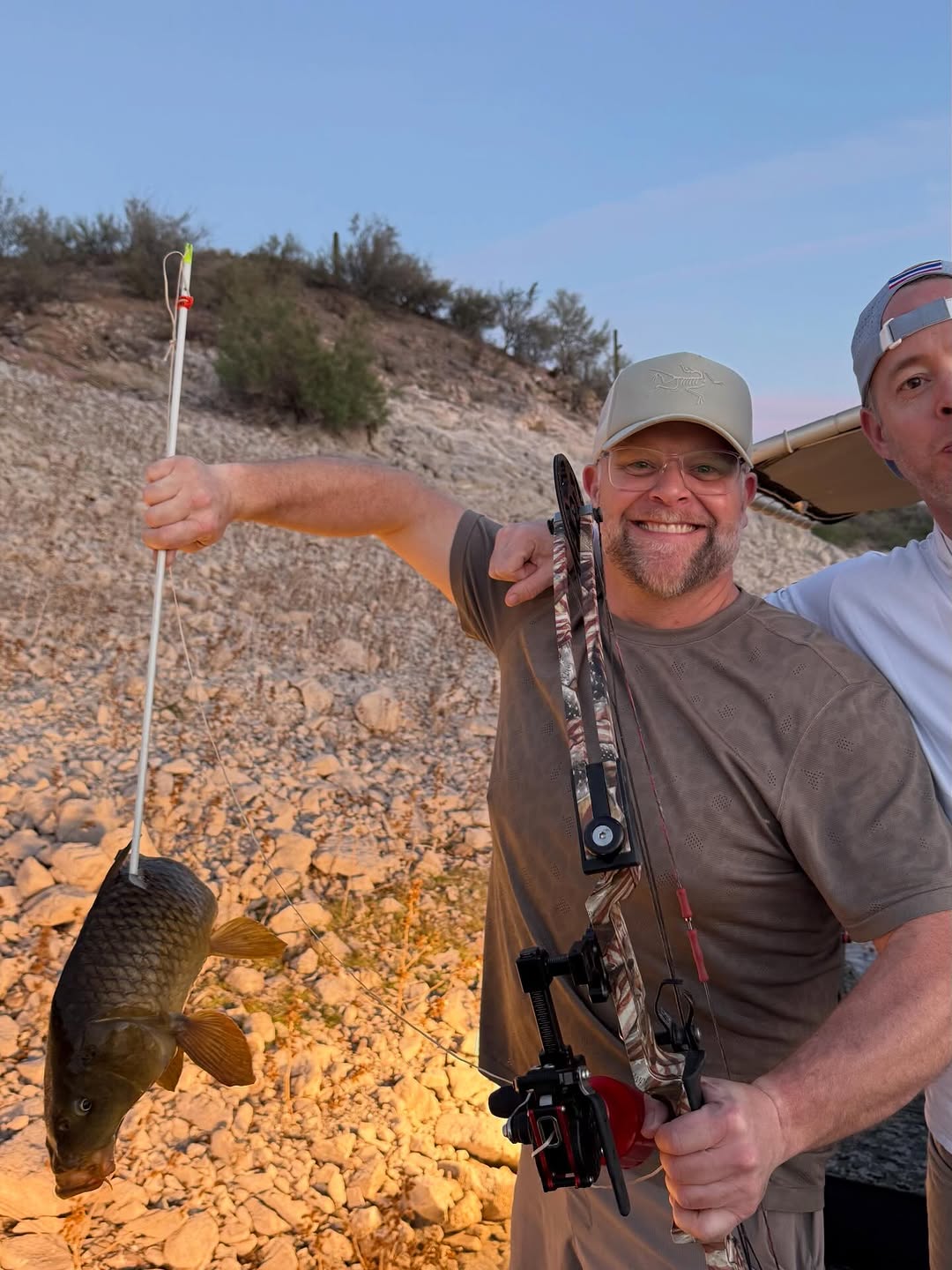 Bowfishing archer displaying caught common carp in Scottsdale Arizona desert terrain
