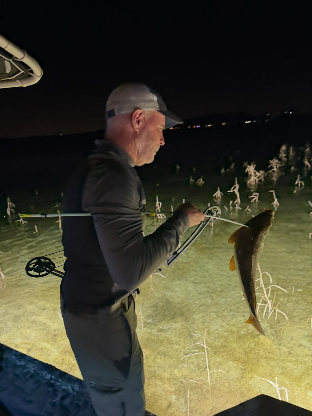 Bowfishing catch with arrow through fish in shallow water at night in Scottsdale AZ