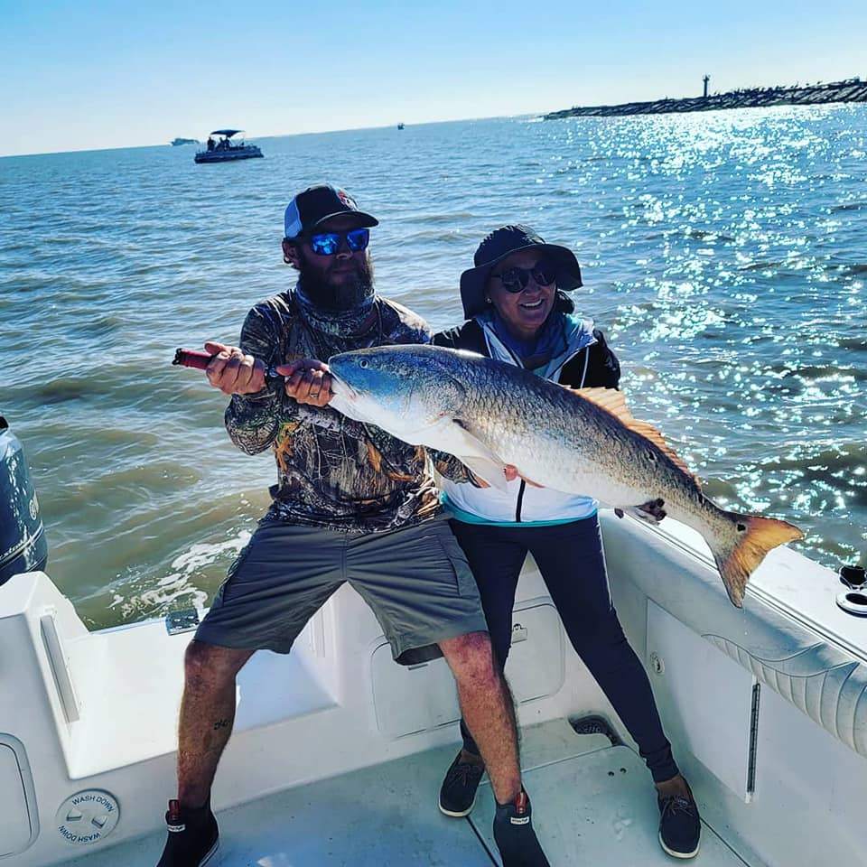 Two anglers standing in water with a fishing rod, catching a large fish in Texas