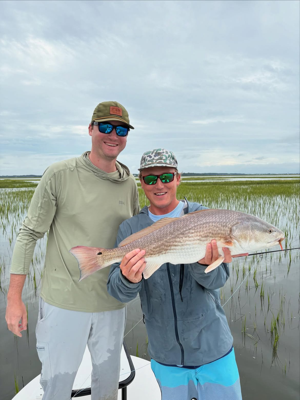 Two anglers holding a redfish on a boat in Mt Pleasant SC waters