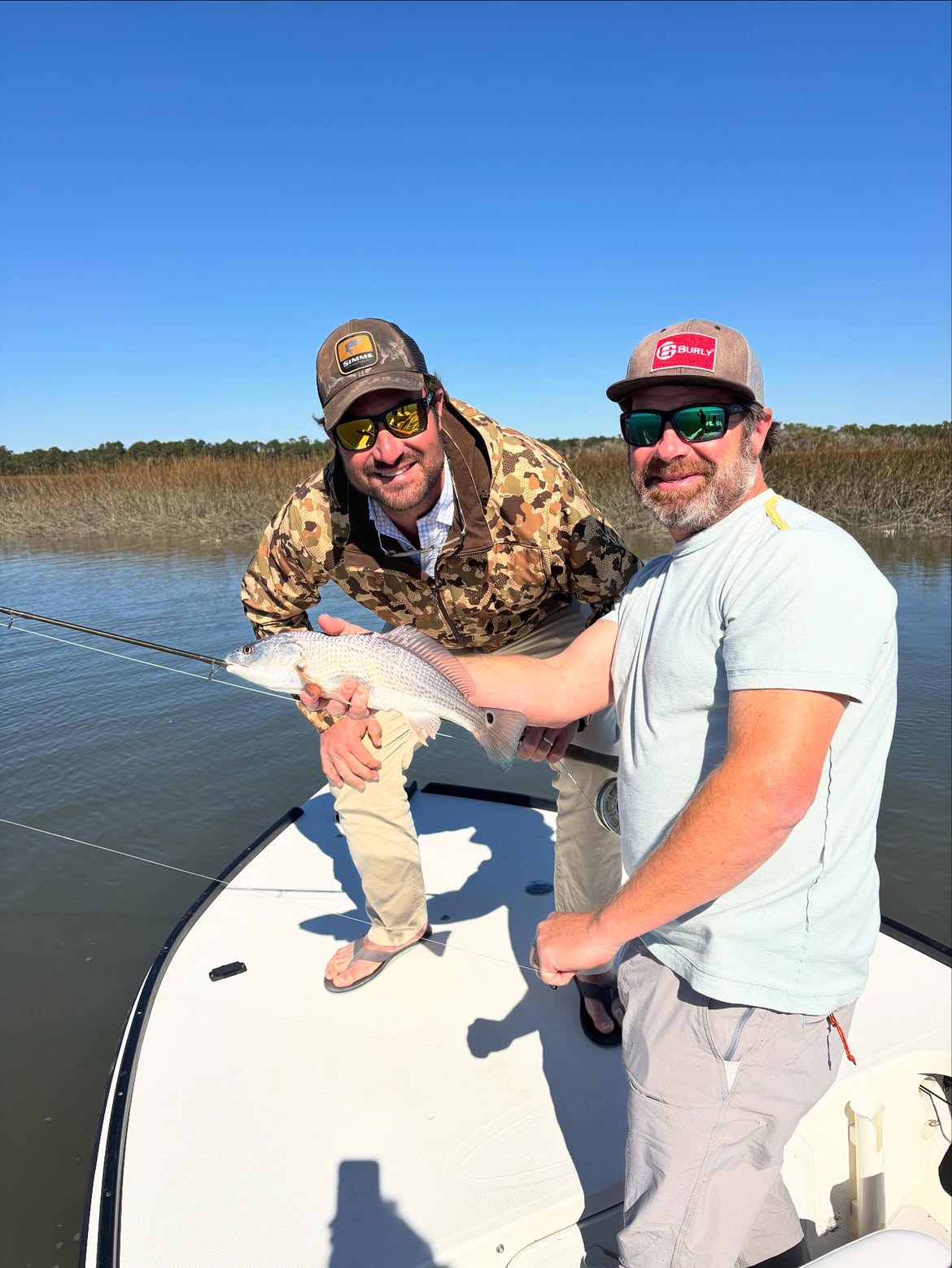 Two anglers holding a redfish on a boat in Mt Pleasant SC waters