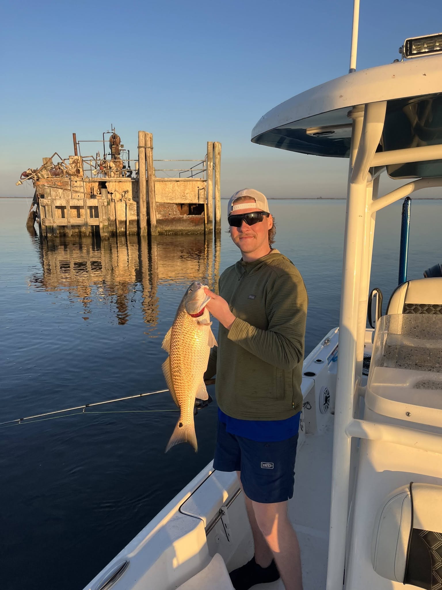 Angler holding caught redfish on fishing boat in Hopedale Louisiana waters