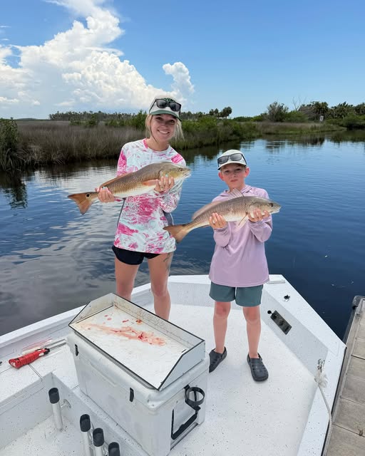Two anglers holding redfish caught while fishing in Spring Hill FL