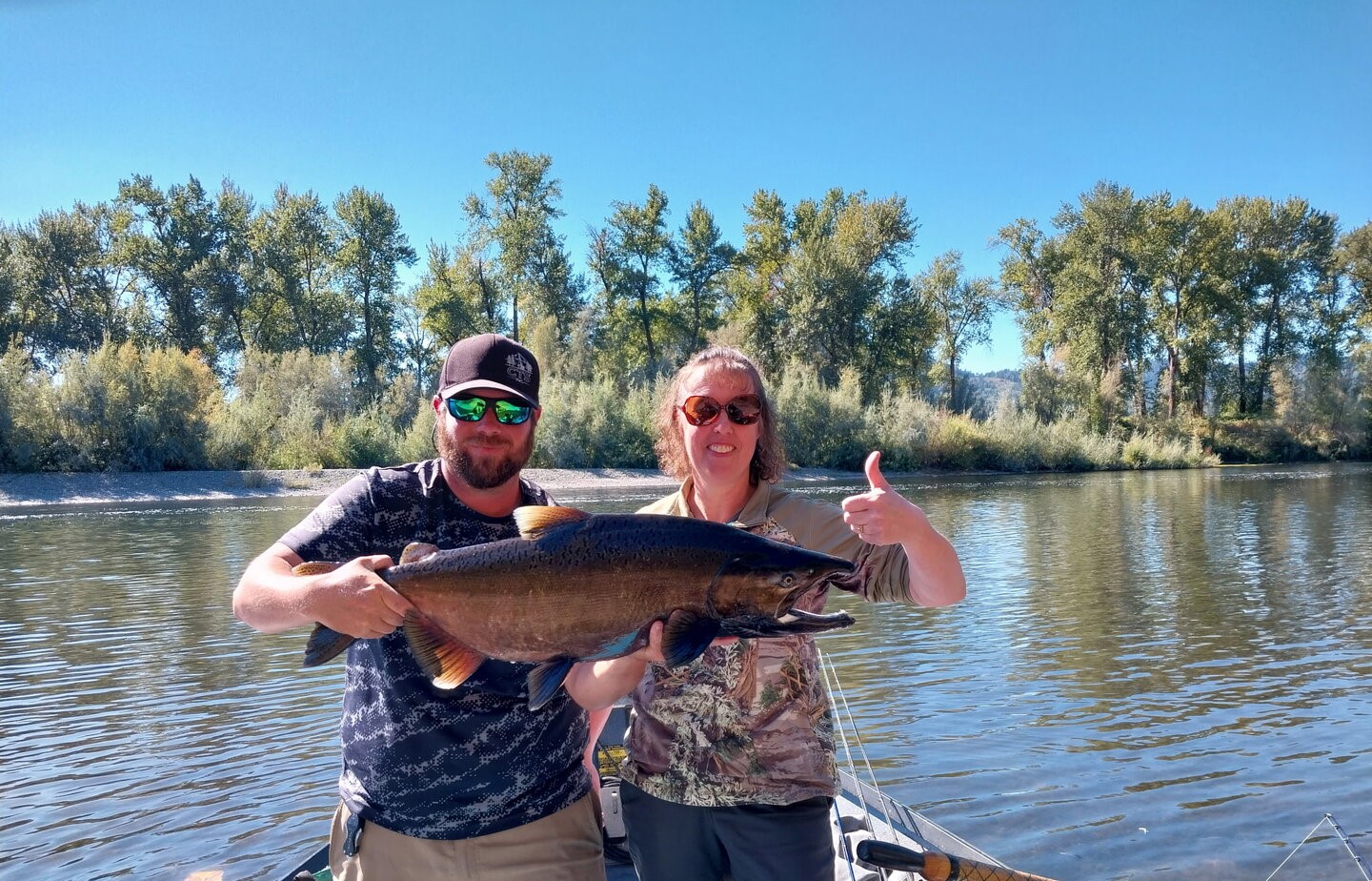 Chinook salmon catch displayed on fishing boat in Grants Pass OR river with trees in background