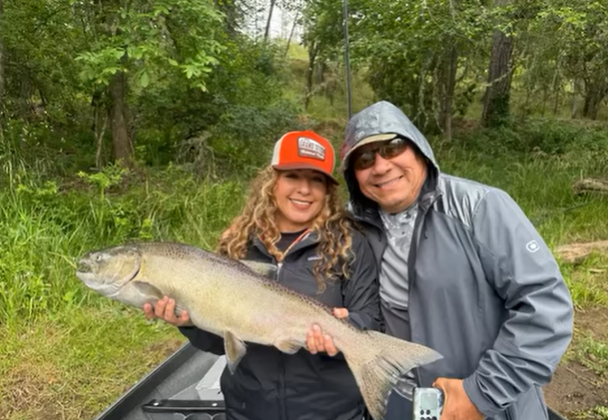 Two anglers displaying a large caught fish during fishing trip in Grants Pass OR