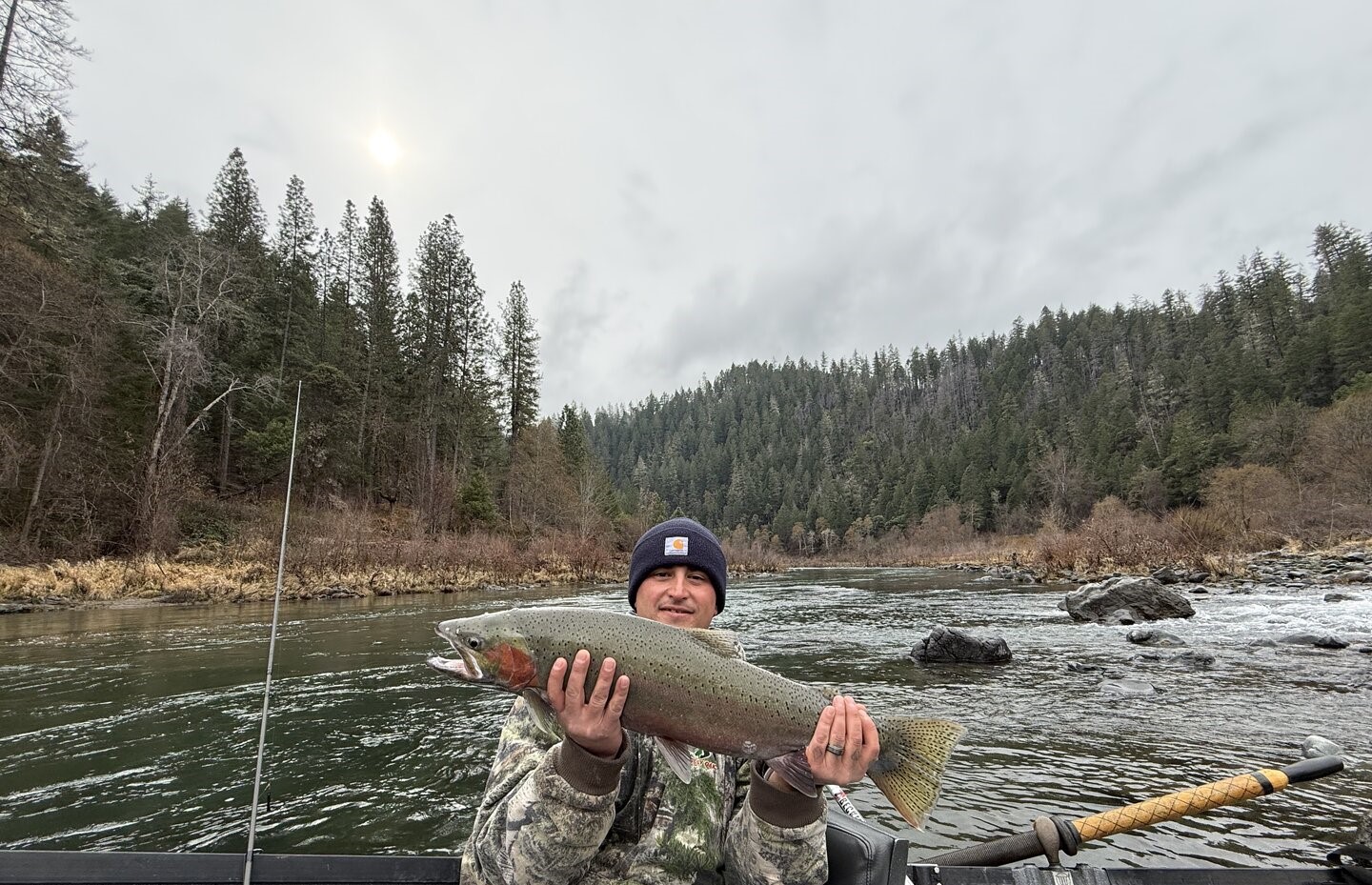 Rainbow trout caught while fishing in Grants Pass Oregon river with forested hills in background