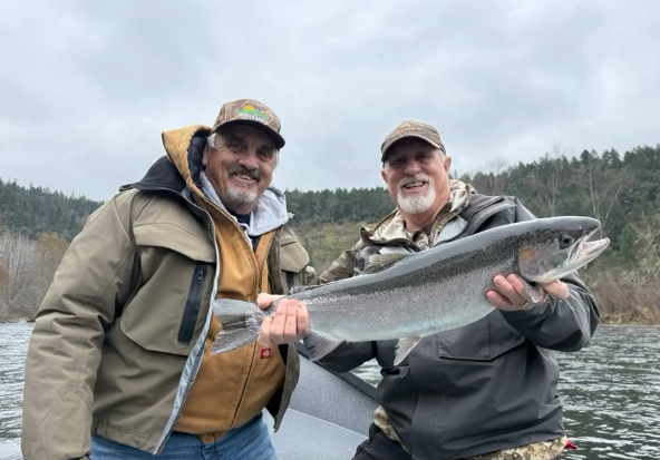 Two anglers proudly displaying a large salmon catch while fishing in Grants Pass, Oregon