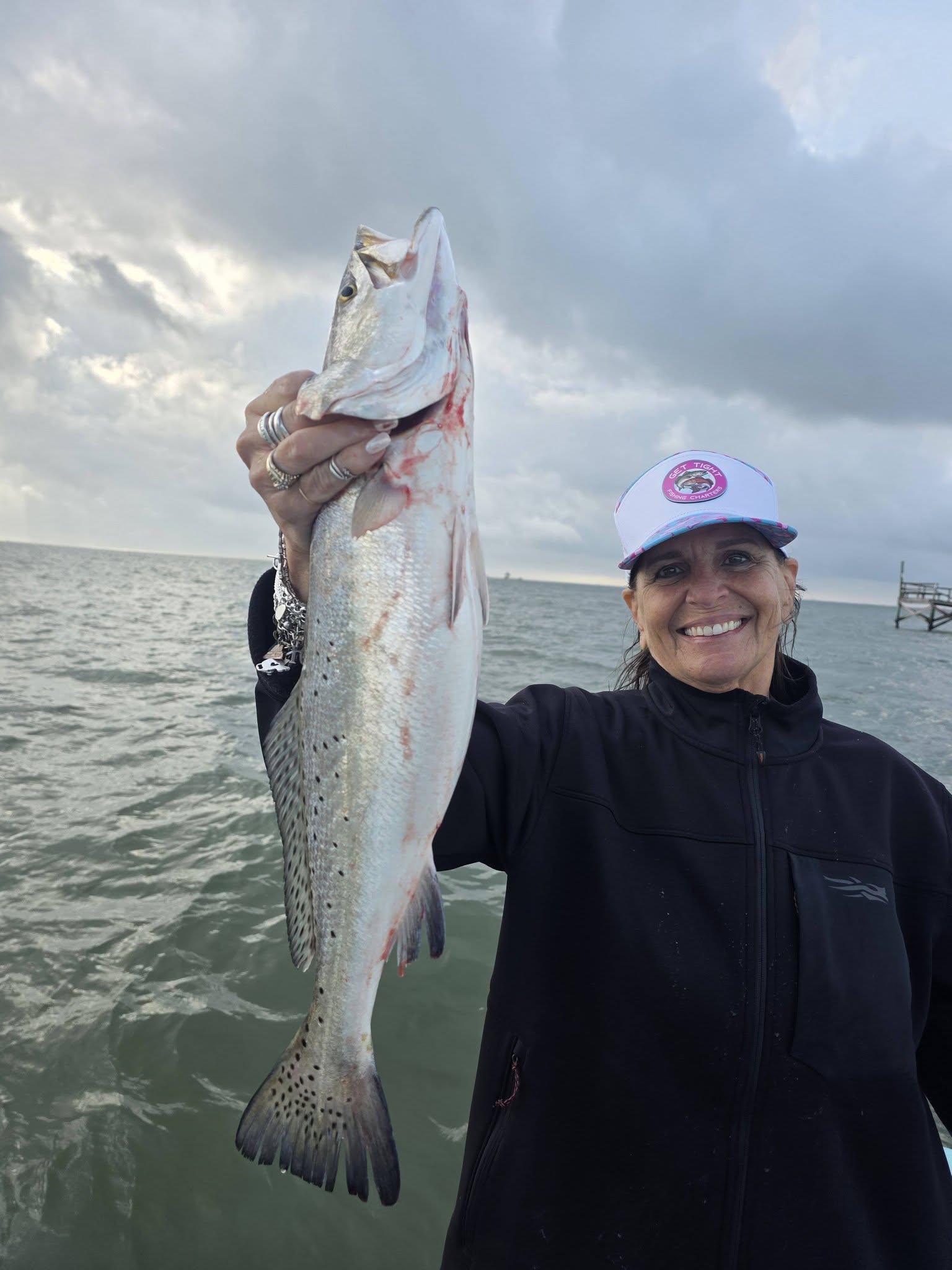 Angler holding freshly caught speckled trout while fishing in Texas City TX waters
