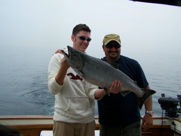 A fisherman holding a large coho salmon in ON.