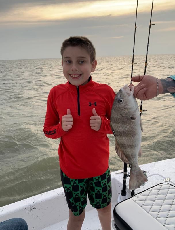 A fisherman holding a black drum fish that is 15 inches long in Falfurrias