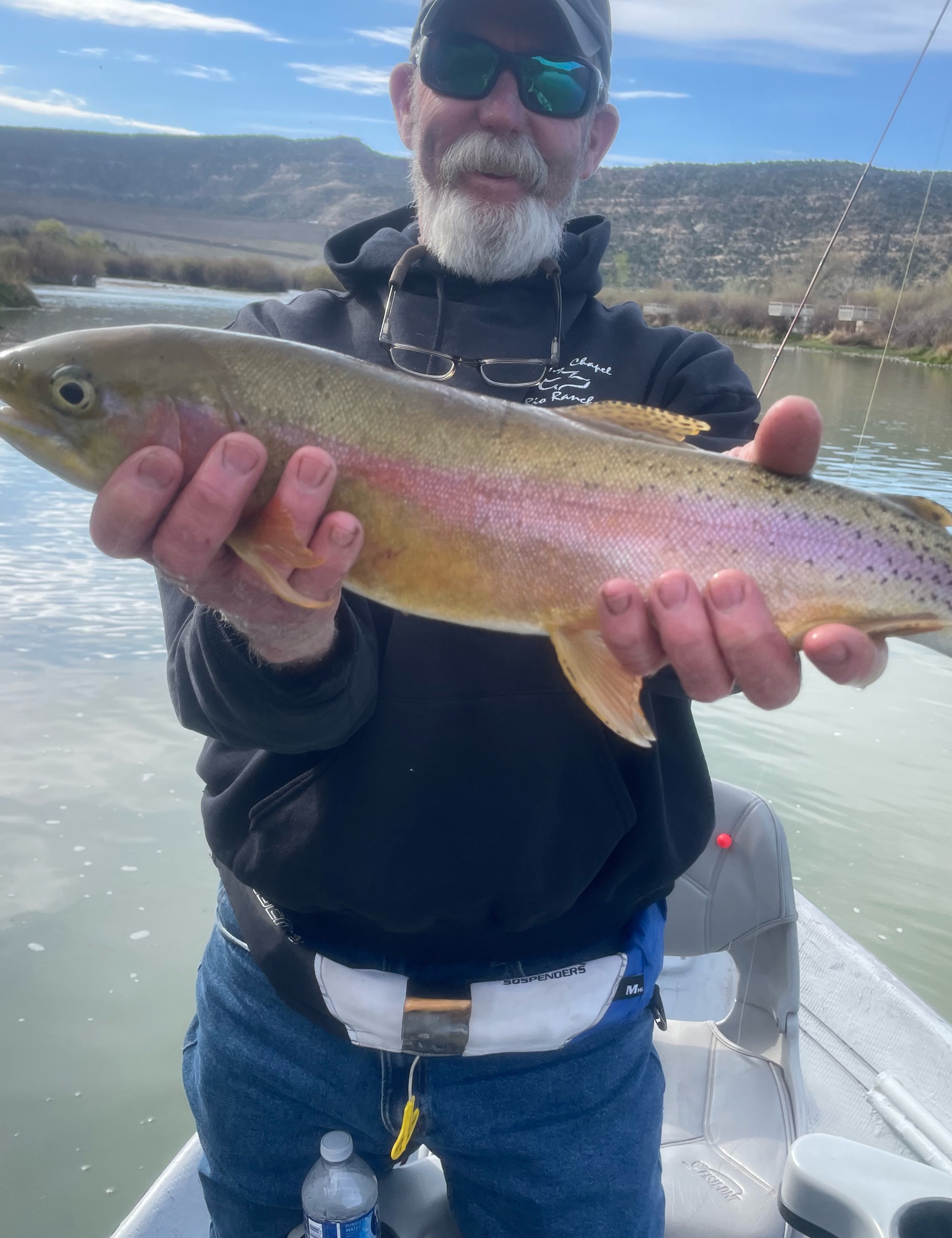 Rainbow trout caught fishing in New Mexico waters with mountainous landscape in background