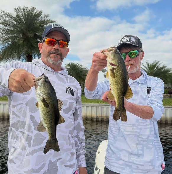 Two anglers displaying caught bass fish in Delray Beach FL