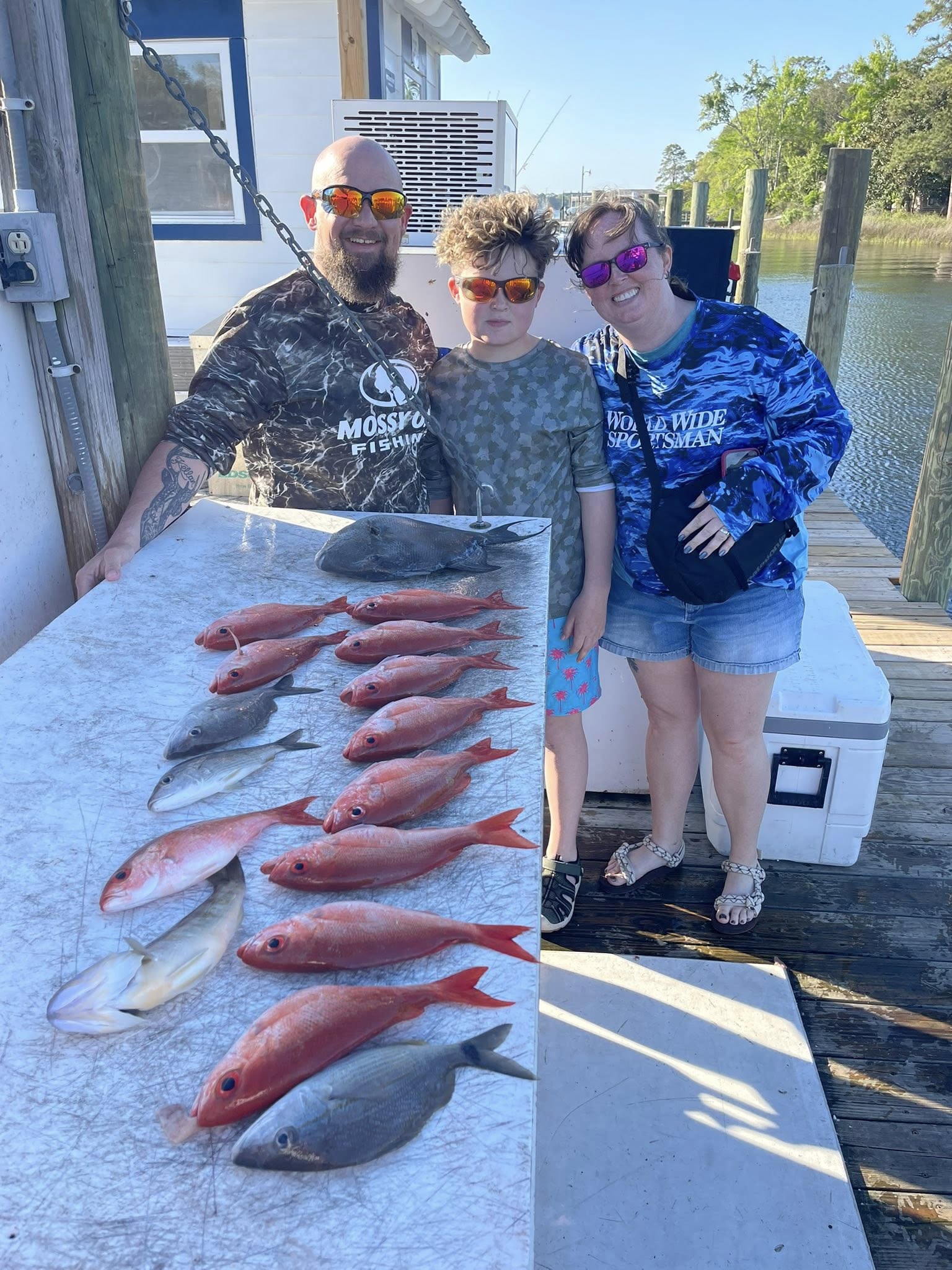 Successful fishing trip in Niceville FL displaying multiple red snapper and other fish species on cleaning table at marina dock
