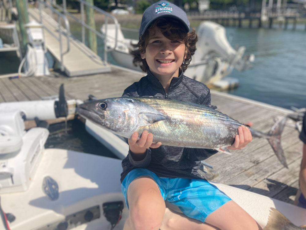 A fisherman holding a large Atlantic Bonito fish in North Carolina.