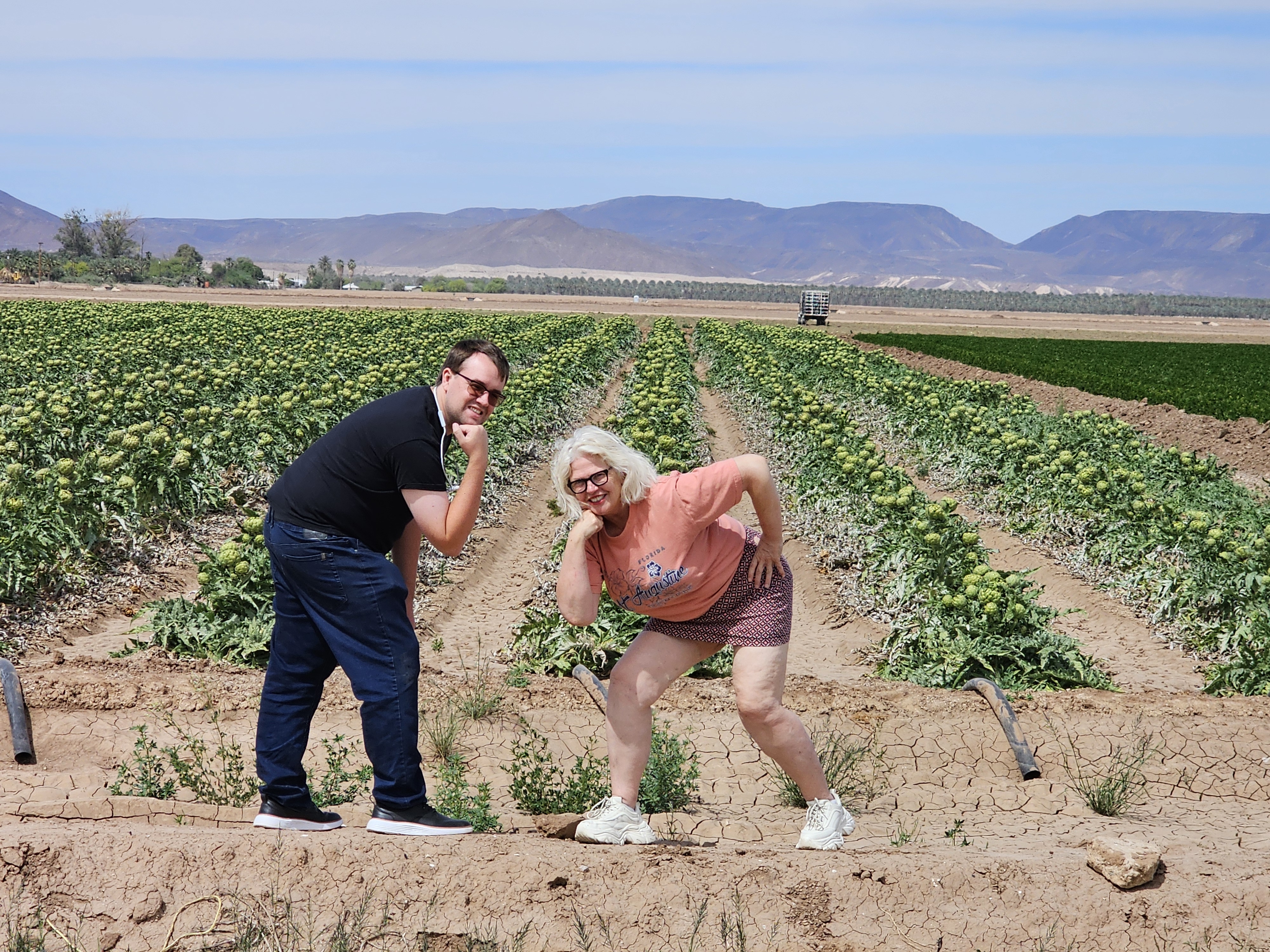 Agricultural tour visitors posing in crop fields with mountains in background in Yuma AZ